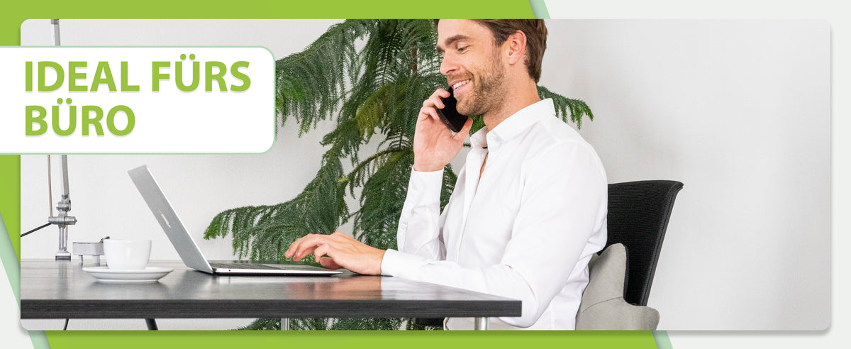 Ideal fürs Büro: Der Mann telefoniert und arbeitet an einem Laptop, sitzt auf einem Stuhl mit dem feela Rückenkissen in Silber für gesunde Haltung.