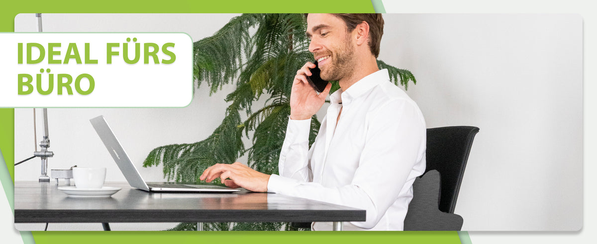 Ideal fürs Büro: Der Mann telefoniert und arbeitet an einem Laptop, sitzt auf einem Stuhl mit dem feela Rückenkissen in Dunkelgrau für gesunde Haltung.